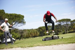 Shot of a frustrated golfer jumping on his golf bag